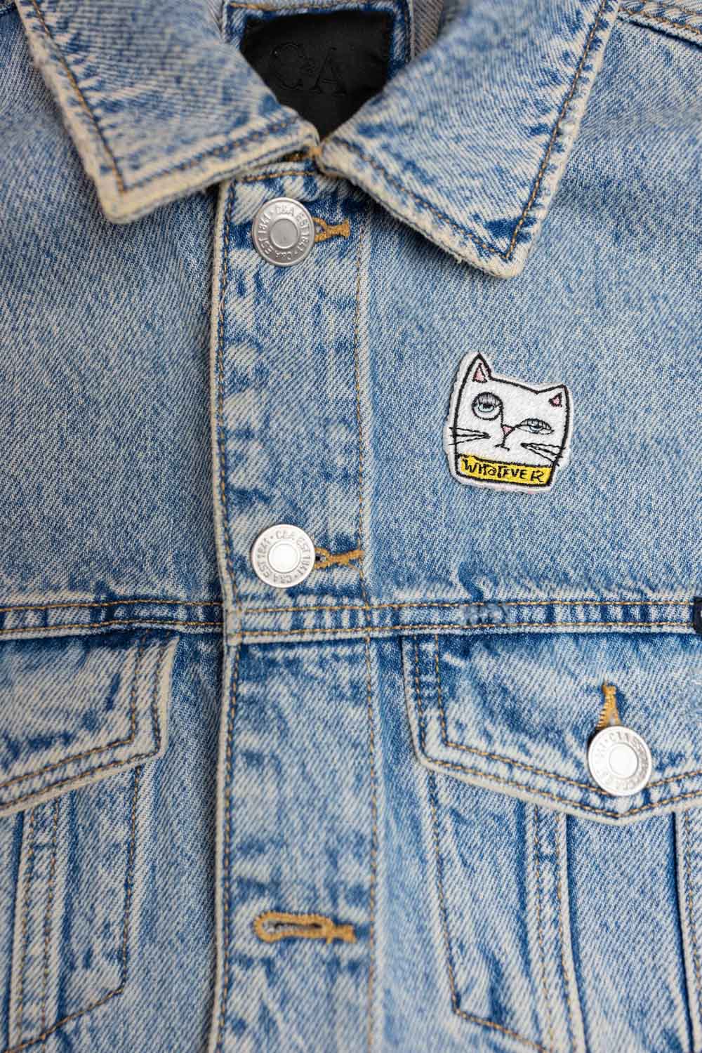 Patch brodat negru cu față de pisică albă și mesajul „Whatever”, un accesoriu ironic și amuzant pentru haine și genți.