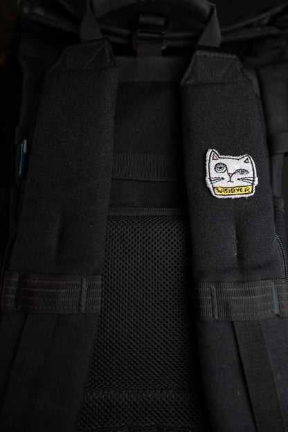 Patch brodat negru cu față de pisică albă și mesajul „Whatever”, un accesoriu ironic și amuzant pentru haine și genți.