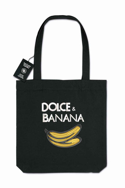 Tote bag brodat negru cu ilustrație de banană și mesajul amuzant „Dolce & Banana”, purtat în aer liber.