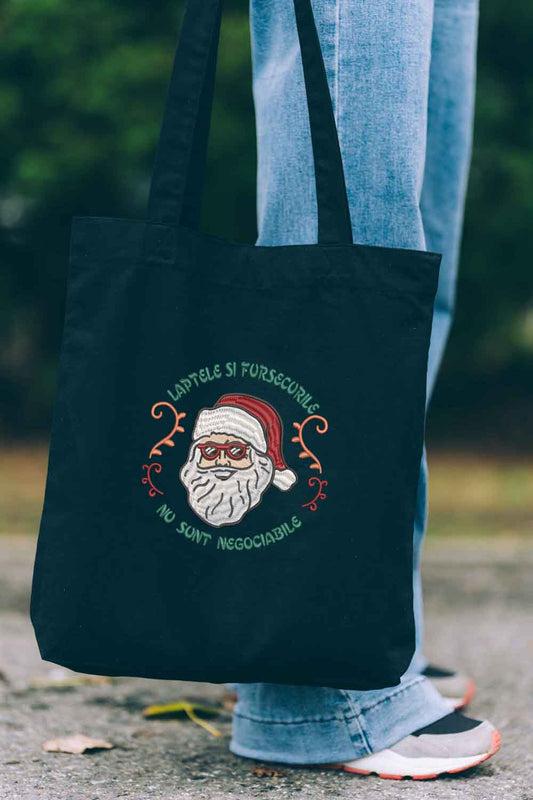 Tote bag brodat negru cu ilustrație de Moș Crăciun și mesaj amuzant despre lapte și fursecuri, un accesoriu festiv pentru perioada sărbătorilor.