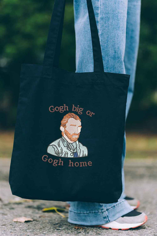 Tote bag brodat negru cu ilustrația lui Vincent van Gogh și mesajul amuzant „Gogh Big or Gogh Home”, purtat în aer liber.