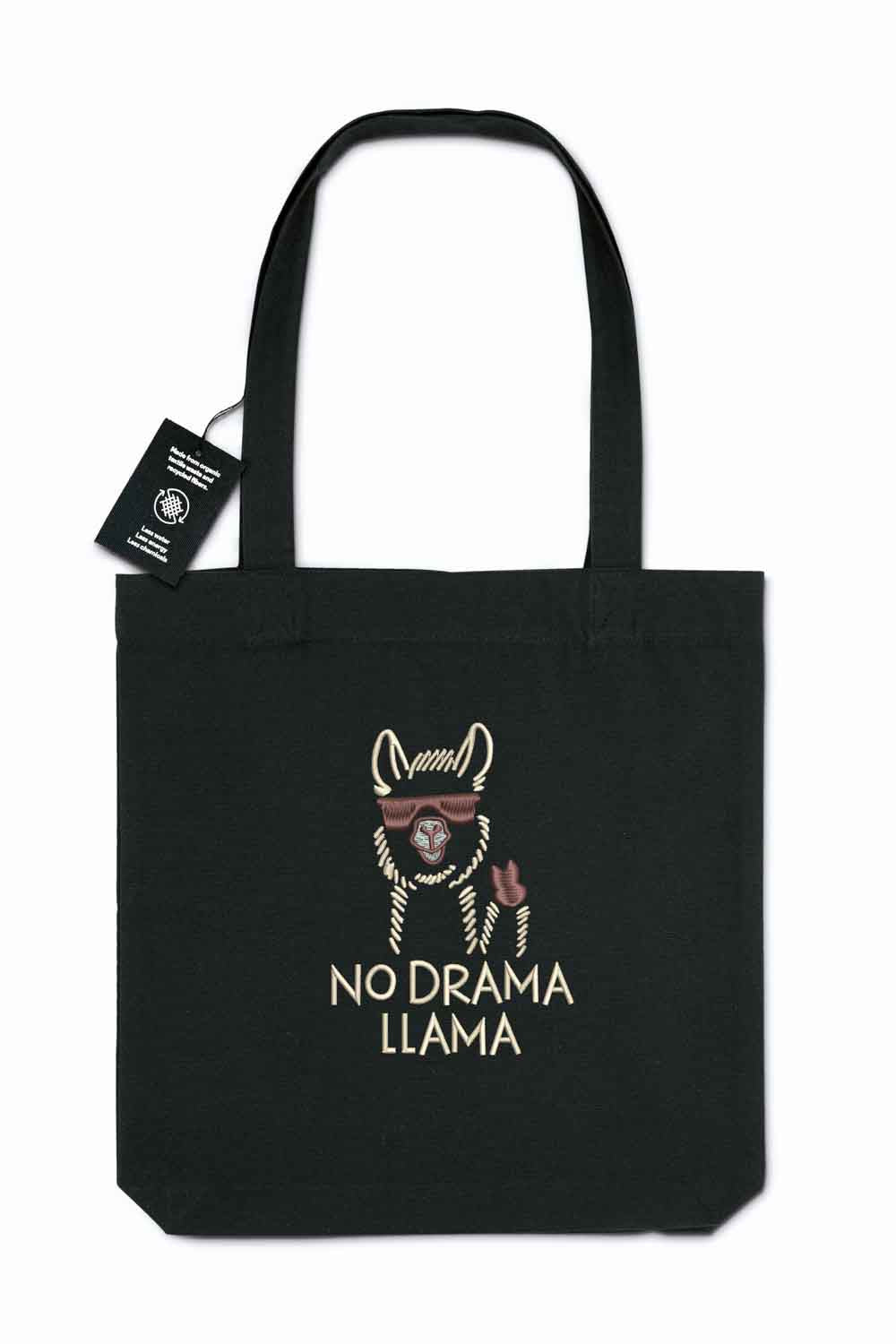 Tote bag brodat negru cu ilustrație de lamă purtând ochelari de soare și mesajul amuzant „No Drama Llama”, purtat în aer liber.