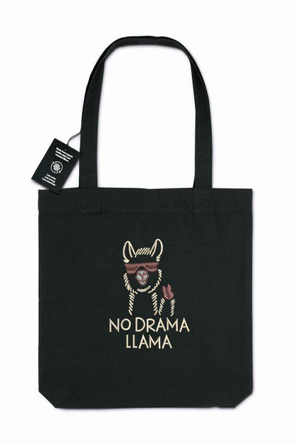 Tote bag brodat negru cu ilustrație de lamă purtând ochelari de soare și mesajul amuzant „No Drama Llama”, purtat în aer liber.