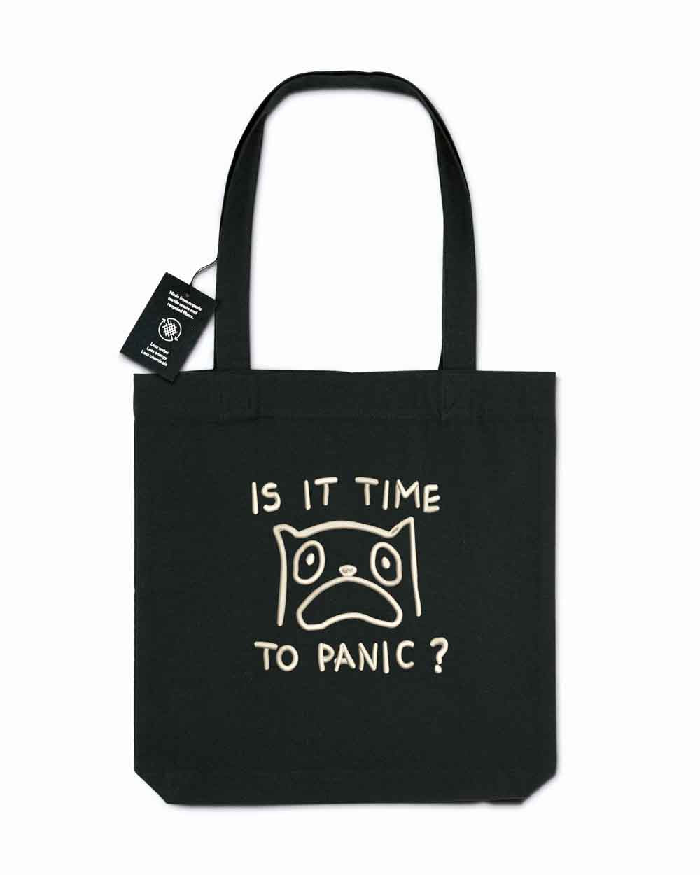 Tote bag brodat negru cu ilustrație amuzantă a unei pisici îngrijorate și mesajul „Is It Time To Panic?”, purtat în aer liber.