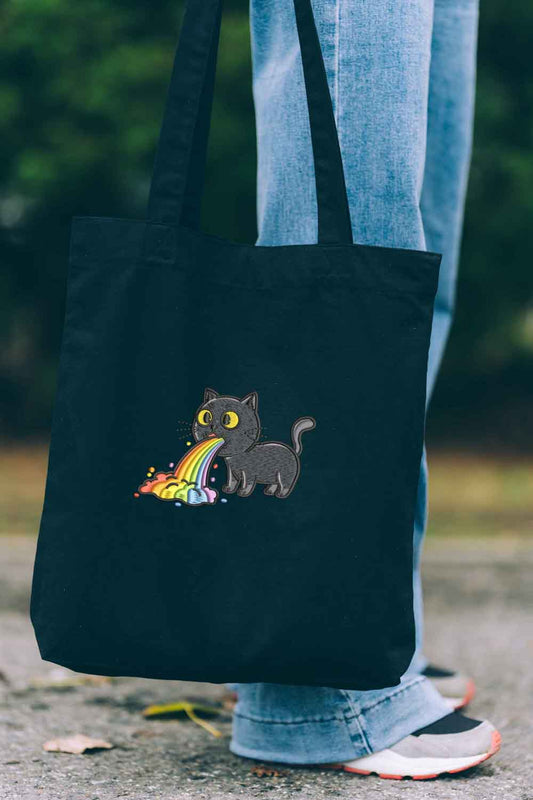 Tote bag brodat negru cu ilustrație amuzantă a unei pisici negre care creează un curcubeu, un design colorat purtat în aer liber.