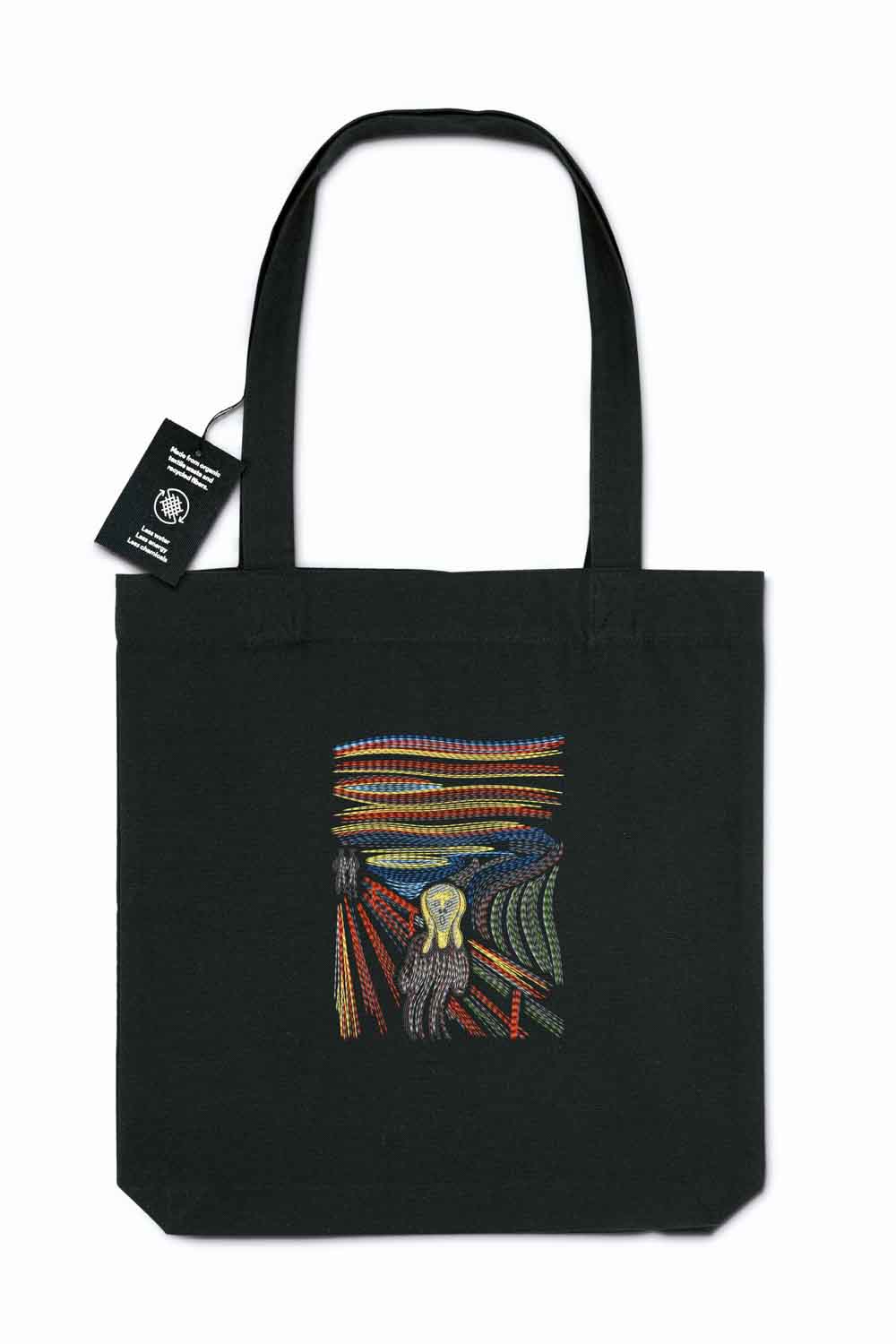 Tote bag brodat negru cu design colorat reprezentând un dinte înconjurat de pene, inspirat de „The Scream”, purtat în aer liber.