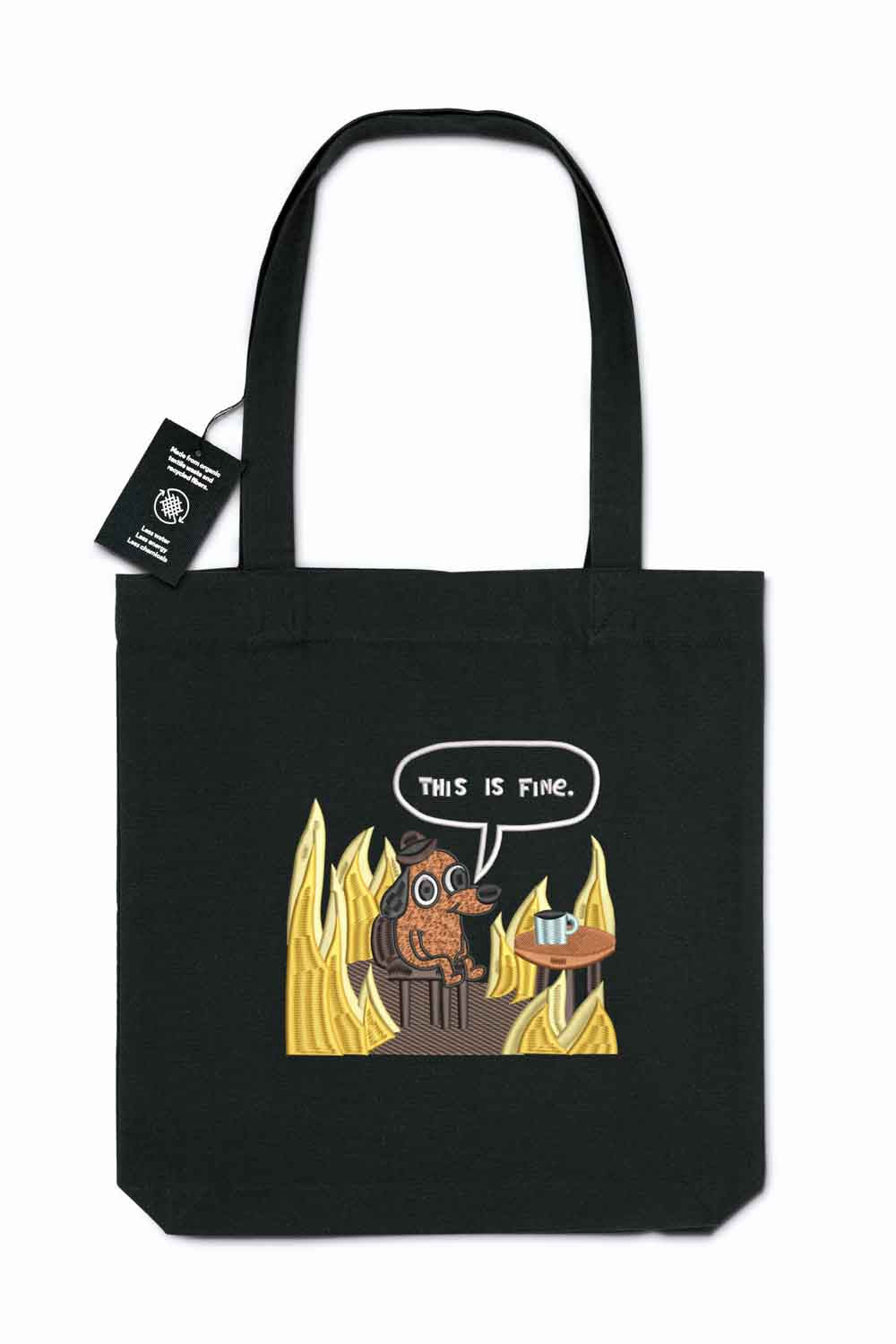 Tote bag brodat negru cu ilustrație amuzantă a unui câine în flăcări și mesajul „This Is Fine”, purtat în aer liber.