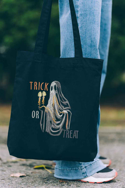 Tote bag brodat negru cu design de Halloween, o fantomă cu două lumânări și mesajul „Trick or Treat”, decorat cu broderie aurie și argintie.