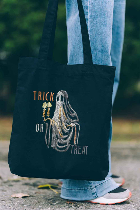 Tote bag brodat negru cu design de Halloween, o fantomă cu două lumânări și mesajul „Trick or Treat”, decorat cu broderie aurie și argintie.
